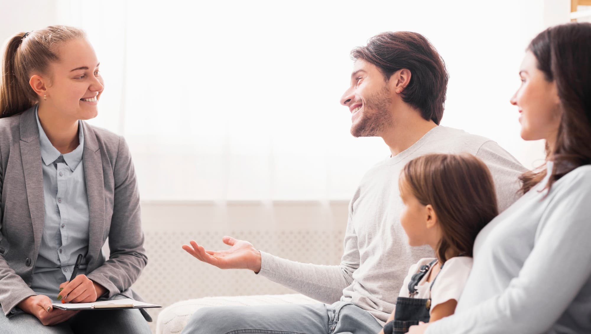 Professional with a clipboard talking with a smiling mother, father, and daughter
