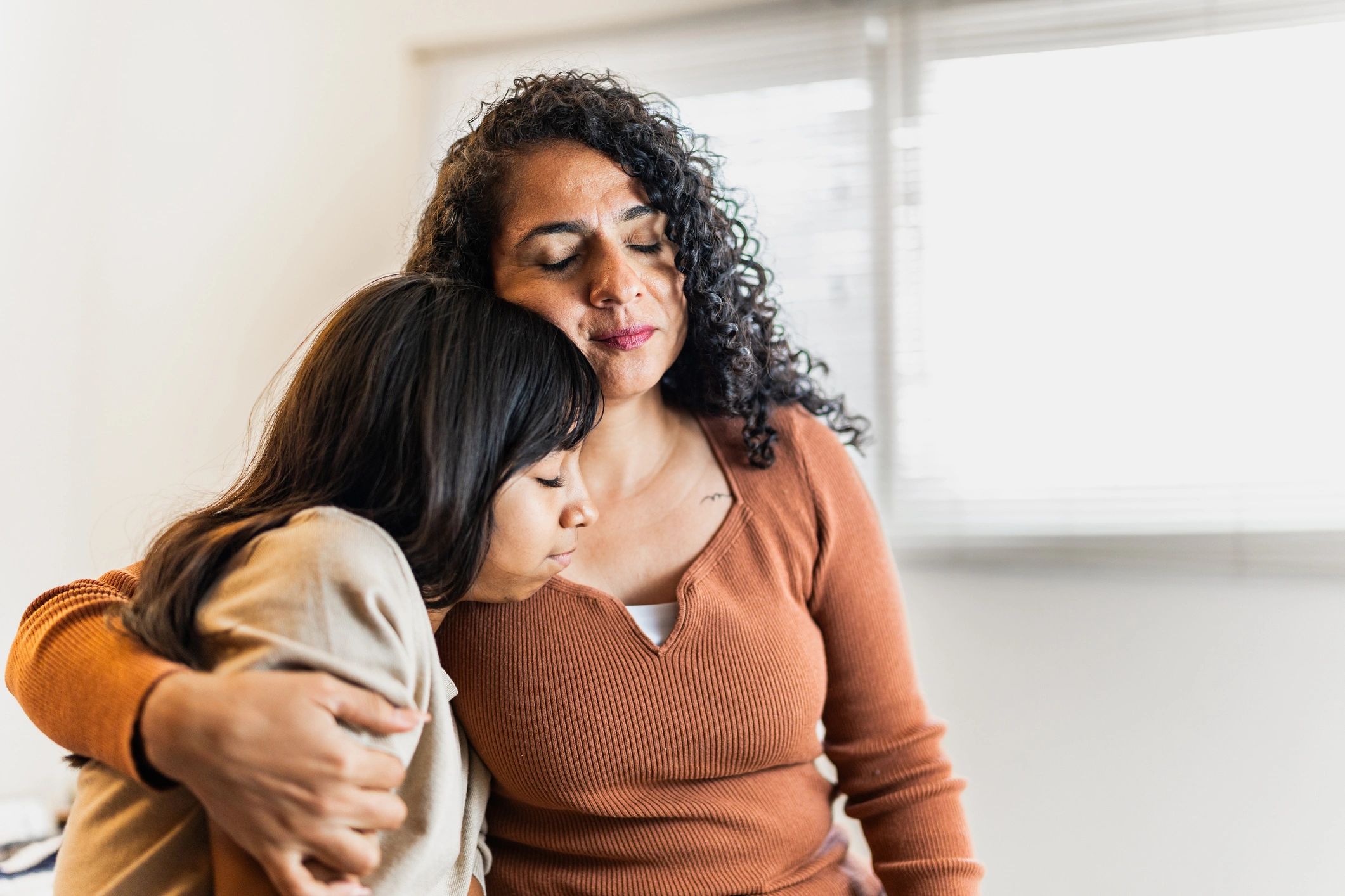 Mother giving support to daughter and embracing at home